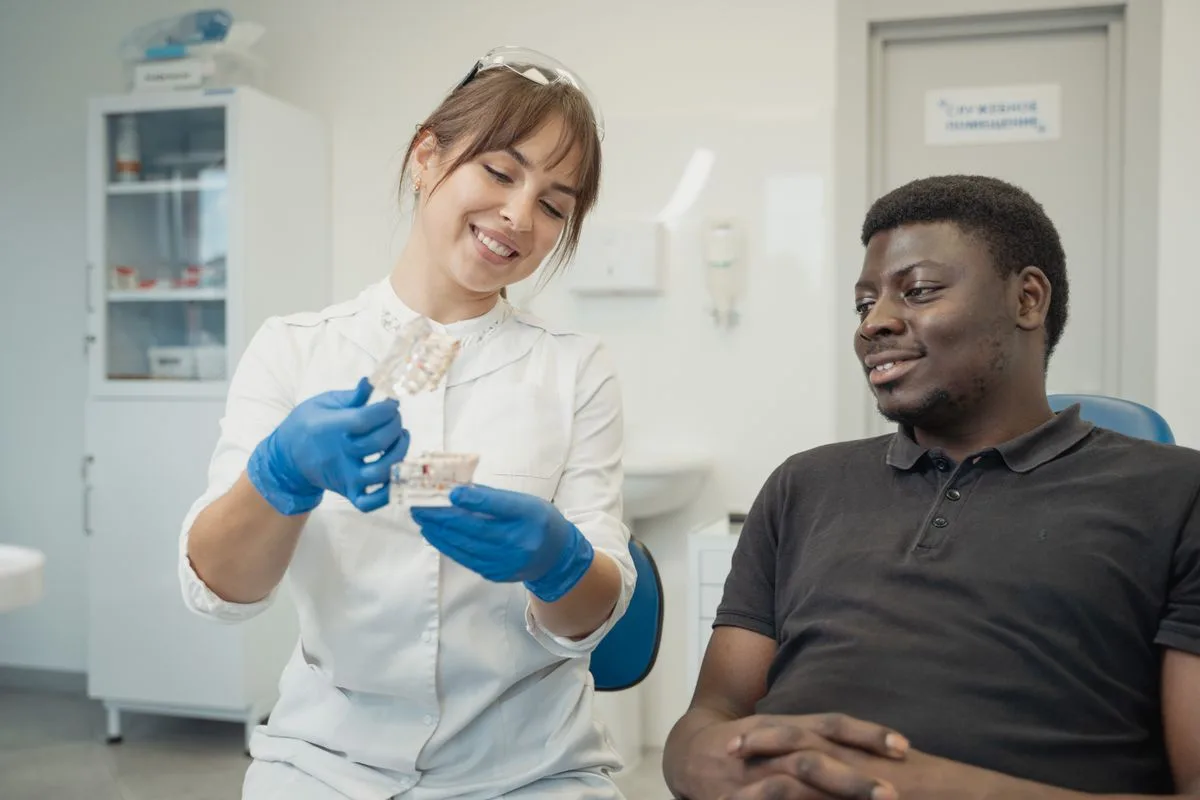 A dentist explaining a dental model to a smiling patient during a consultation