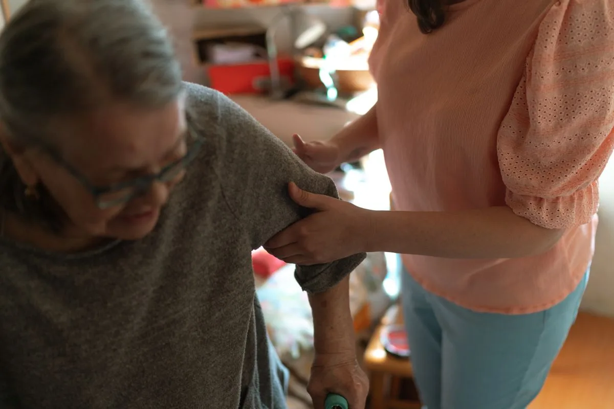 A caregiver offering a steadying hand to an older adult at home