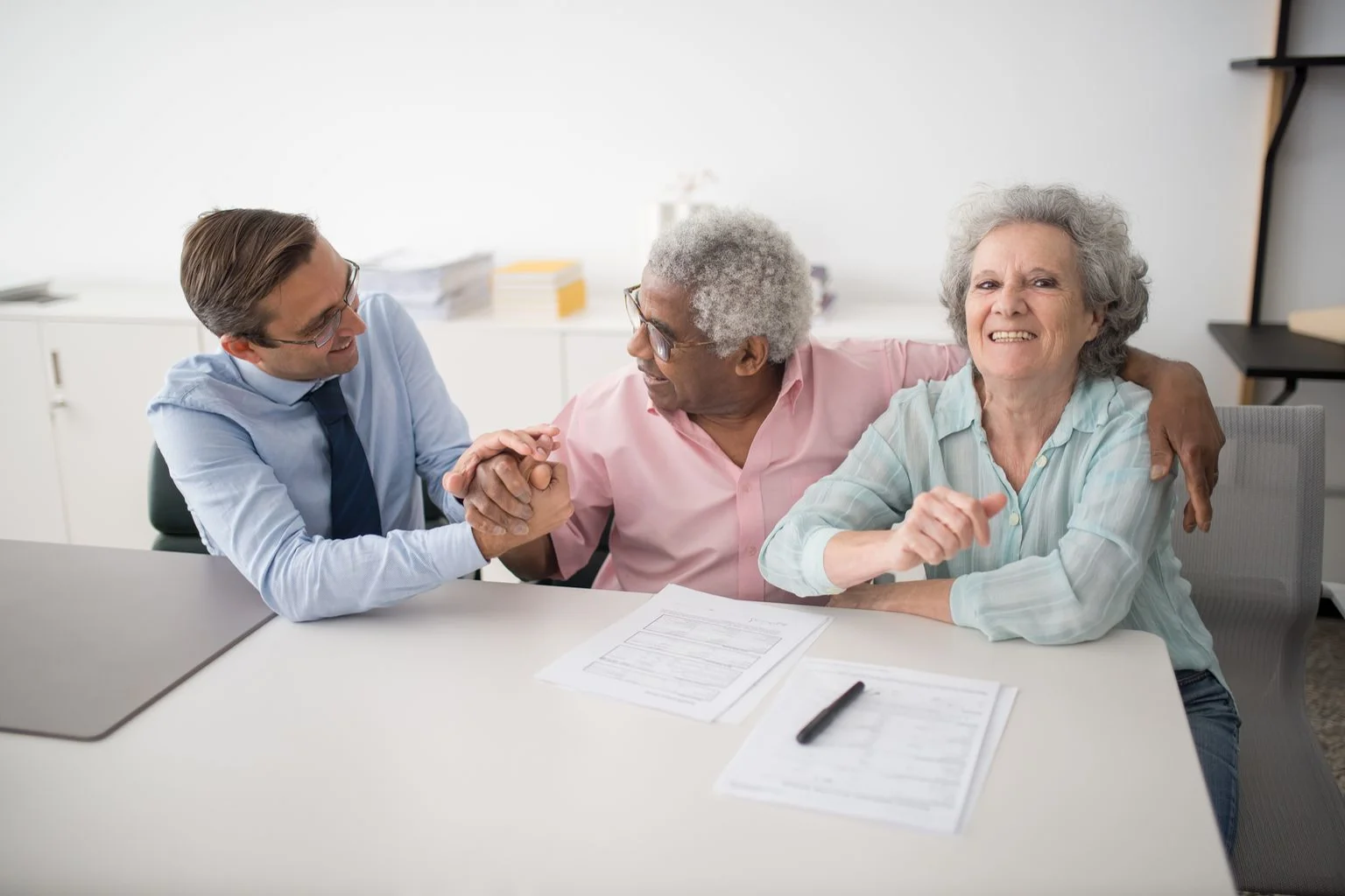 An insurance consultant meeting with a smiling older couple at an office table