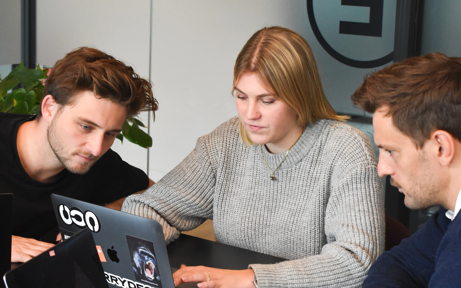 Three colleagues reviewing a project together on a laptop